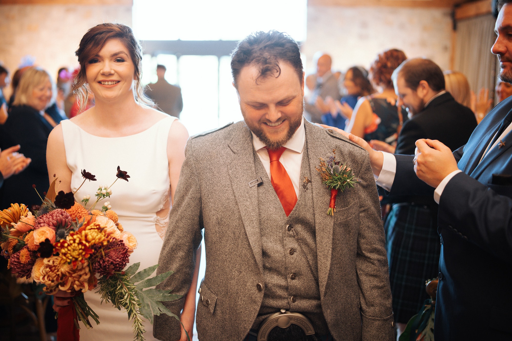 Bride and groom walking back down the aisle together, smiling, at their wedding ceremony